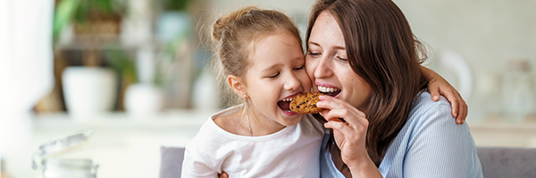 Madre e hija comiendo felices una galleta Madre e hija comiendo felices una galleta